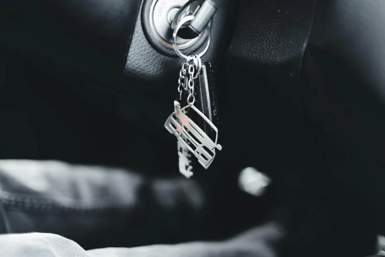 Car keys are in the ignition with a car-shaped keychain
